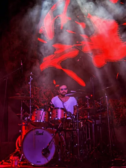 The intensity of a drummer, bathed in the fiery red of the stage. My goal is to capture the power and rhythm that drives the entire performance.