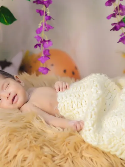 A happy, sleepy newborn smiling in their dreams. This candid shot captures the pure joy of a baby, even while they are resting.