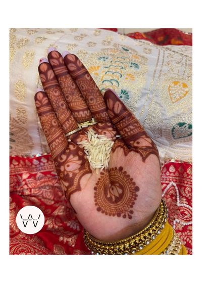 A close-up of the Teej henna stain, holding traditional rice grains as part of the puja.