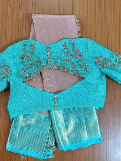 The full view of the turquoise blouse with its elaborate back and sleeve embroidery, laid over a contrasting pink Kanjeevaram saree.