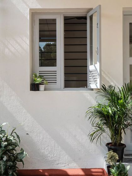 Light and shadow play across the building's simple white facade. The louvered window design is a detail I used throughout the Anganwadi to ensure constant, natural ventilation while maintaining security, a core principle of my climate-responsive approach.