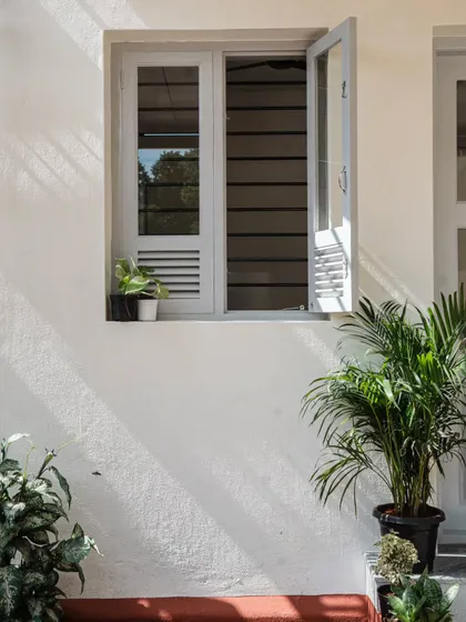 Light and shadow play across the building's simple white facade. The louvered window design is a detail I used throughout the Anganwadi to ensure constant, natural ventilation while maintaining security, a core principle of my climate-responsive approach.
