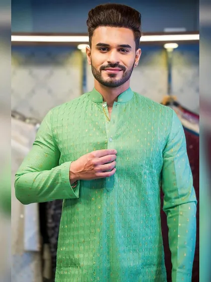 A client, Ayush Khatri, looking pleased in a bright green textured kurta. The fit is perfect, highlighting the benefits of custom tailoring.