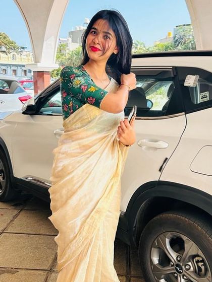 A client looking chic in a simple off-white saree paired with a contrasting green floral embroidered blouse.