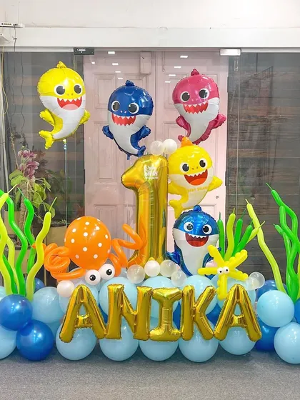 Baby Shark, doo-doo-doo! This super popular theme is always a hit with the little ones. The whole shark family is here, swimming in a sea of blue balloons with the birthday girl's name in gold.