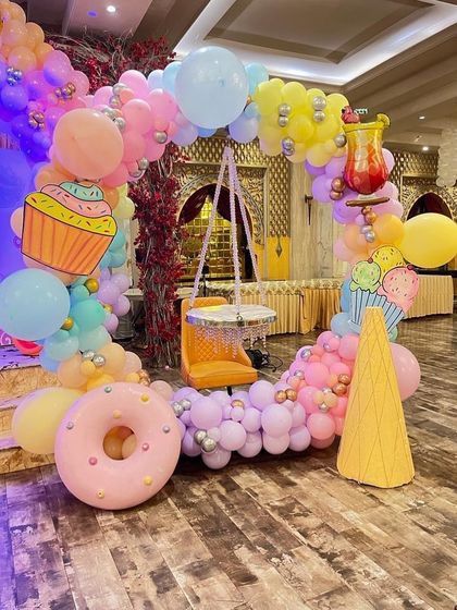 A unique candy-themed seating arrangement made of balloons, featuring a donut, ice cream cone, and cupcake props.