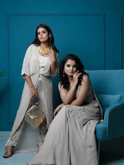 Another view of the coordinated Diwali looks against a bold teal background. The neutral tones of the outfits pop beautifully, highlighting the intricate embroidery and modern silhouettes.