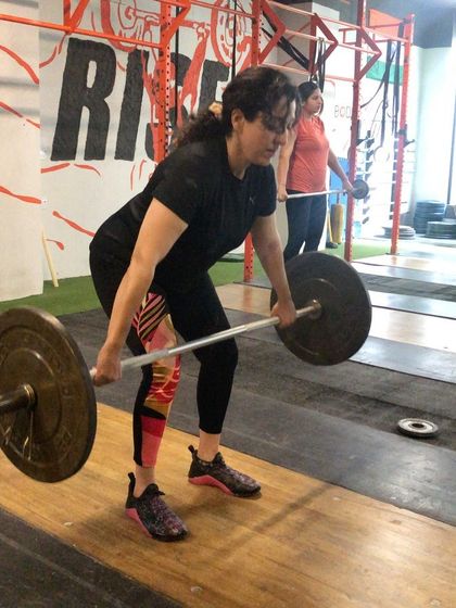 A female client setting up for a hang snatch. Proper starting position is key, and we focus on keeping the back straight and chest up to ensure an efficient pull.