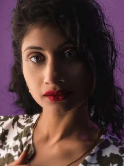 A close-up from a studio session where I experimented with lighting and a bold purple background. I focus on retouching the mood and colors to make the portrait pop, not change your face.