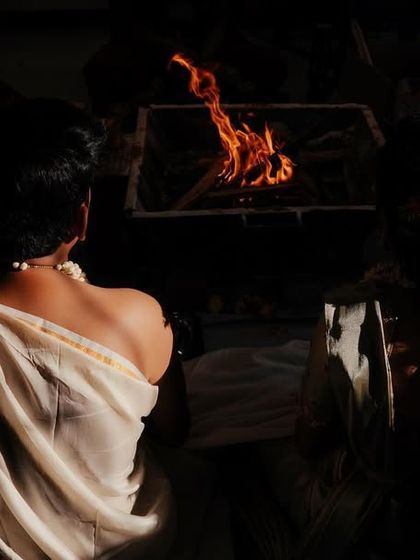 A creative, low light shot from behind the couple as they sit before the sacred fire, emphasizing the spiritual nature of the wedding ceremony.