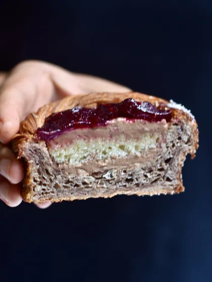 Our take on the classic Lamington, reimagined as a croissant cup. It features layers of dark chocolate coconut mousse, soft vanilla cake, and a bright berry jelly, all encased in our flaky croissant pastry.