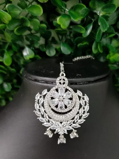 A sparkling American Diamond maang tikka with a floral and crescent design, perfect for a reception look.