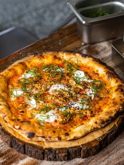This pizza is loaded with flavor, featuring creamy cheese, savory toppings, and fresh scallions on our signature wood-fired crust.
