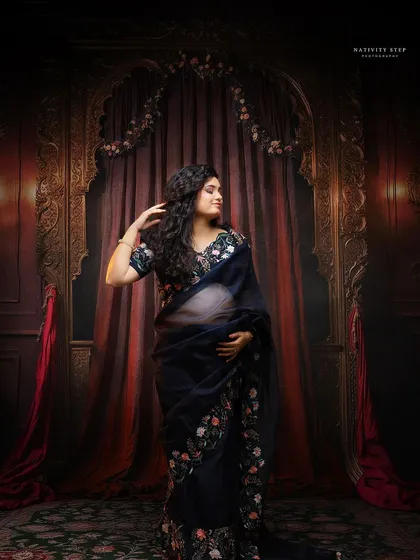 A stunning portrait in a sheer black embroidered saree. This shot combines traditional elegance with a touch of modern glamour against a royal backdrop.