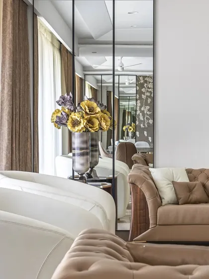 The strategic placement of a tall, paneled mirror not only adds a decorative element but also captures and reflects light, making the entire living area feel brighter and more expansive.