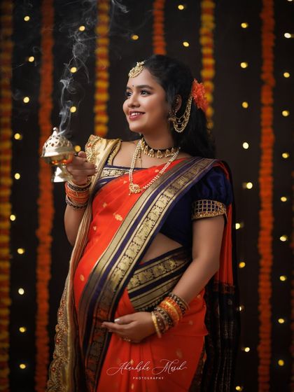 A close-up from our festive marigold setup, capturing the mother's joyful smile as she holds a traditional brass lamp, surrounded by warm light.