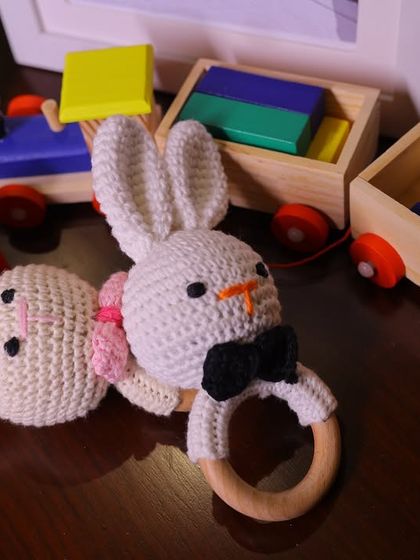 A pair of adorable handmade crochet bunny rattles, one with a bow tie and one with a pink bow. These custom toys were part of the decor and a gift for the baby.