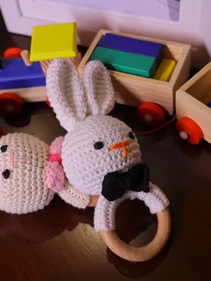 A pair of adorable handmade crochet bunny rattles, one with a bow tie and one with a pink bow. These custom toys were part of the decor and a gift for the baby.