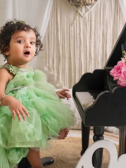 A sweet song for her first birthday. This candid shot captures a moment of wonder and expression during a fun and creative first birthday photoshoot.