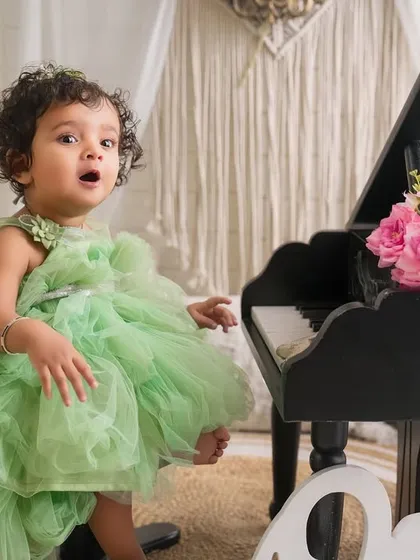 A sweet song for her first birthday. This candid shot captures a moment of wonder and expression during a fun and creative first birthday photoshoot.