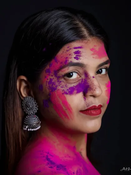 A bold and fashionable Holi portrait. The combination of red lipstick and vibrant pink and purple powders creates a stunning, high-fashion look.