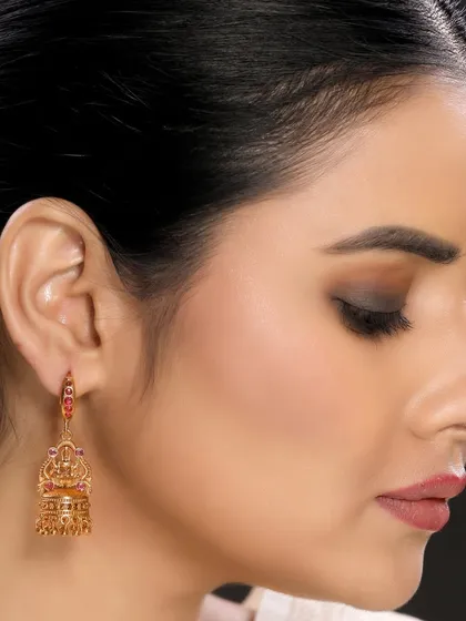 A side profile of a model wearing ornate temple jhumkas. The focus on the earring against the model's hair provides a clear and appealing view for potential buyers.