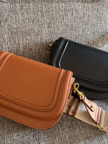 The brown and black Noble bags displayed together. This view highlights the curved saddle shape and the clean, structured lines of the design.