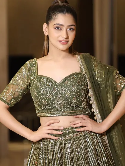A close-up of the beautifully embroidered blouse of our olive green lehenga. The sweetheart neckline and detailed sleeves add to its traditional charm.