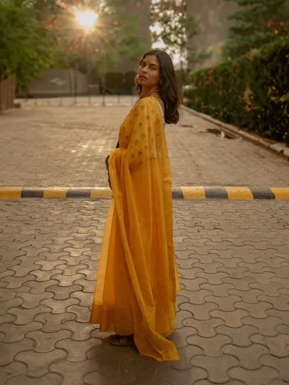 A stunning golden hour portrait of a woman in a vibrant yellow saree, captured on a paved path. This shot showcases my love for using natural light to create atmospheric and elegant outdoor portraits.
