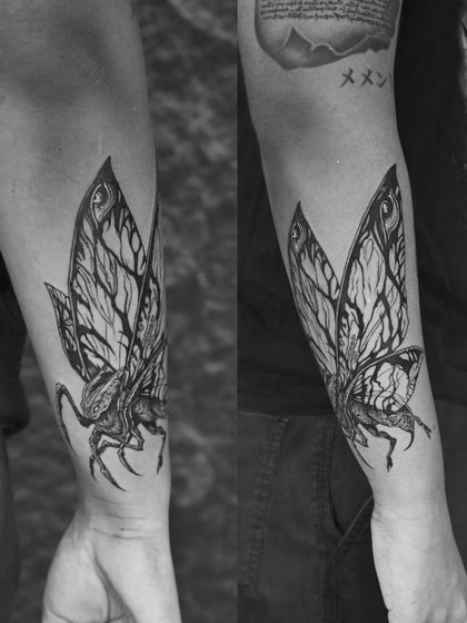 A detailed black and grey tattoo of Mothra, the giant moth from Japanese cinema. The intricate wing patterns and powerful form make for a stunning forearm piece.
