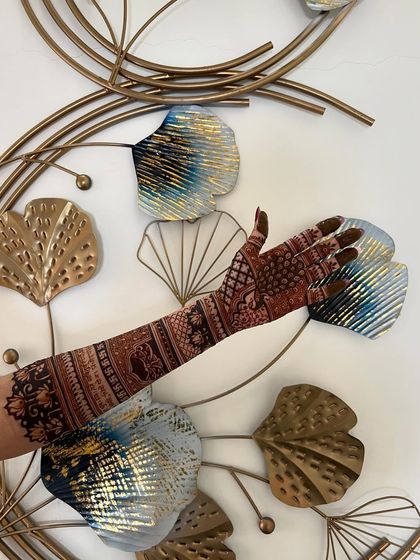 An artistic shot of a full-arm mehendi against a decorative wall piece, blending art with art.
