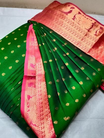 A bottle green saree with a pink and red border. The pleats are done to perfection, making it ready for any special occasion.