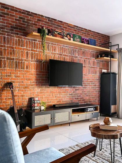 For this project, we created an industrial-chic living room with an exposed brick accent wall. The floating wood shelves and metal-accented TV console complete the look, perfect for a client with a modern, urban style.