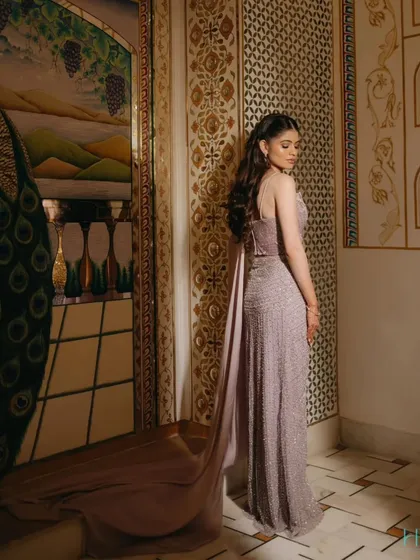 An elegant bridal portrait showcasing the beautiful drape and trail of her lavender gown against an ornate, artistic wall.