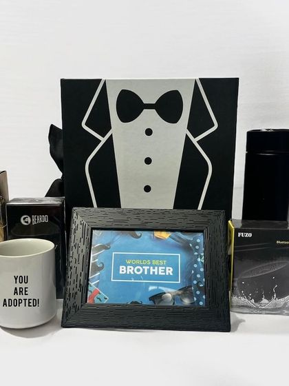 A classic gift hamper for a brother, featuring a "World's Best Brother" photo frame, a cheeky "You are adopted!" mug, a Bluetooth speaker, and Ferrero Rocher chocolates.
