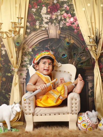 Even little gods need to kick their feet up. This playful shot captures the fun side of a Krishna-themed photoshoot, complete with a miniature cow and makhan pot props.