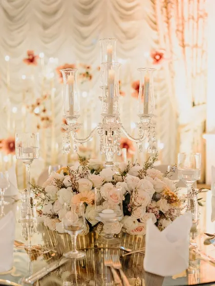 A close-up of a classic and elegant table centerpiece, featuring white roses and a crystal candelabra.