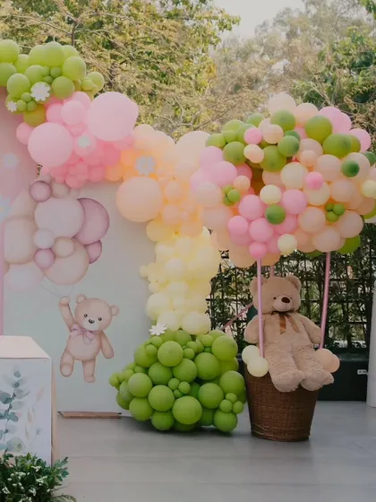 A creative hot air balloon made of balloons, with a teddy bear in the basket, adding a whimsical touch to the decor.