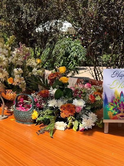 The welcome table for the Holi party, featuring a colorful art print and a beautiful arrangement of seasonal flowers.