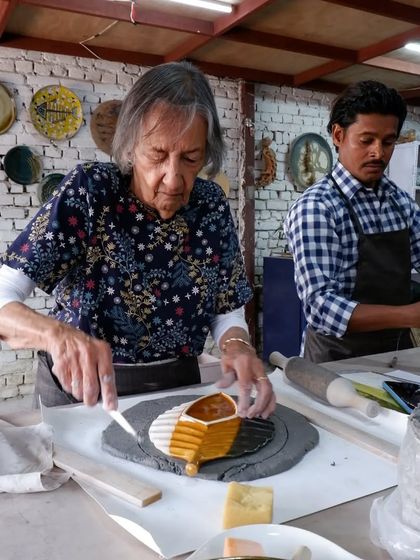 Here, a student is using different colored clays to create a decorative pattern on a slab. This is a great way to explore color and design in hand-building.