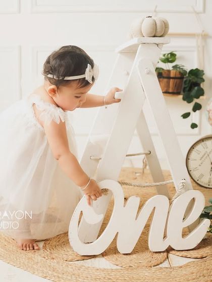 The birthday girl explores the "One" sign during her minimalist and elegant first birthday shoot.