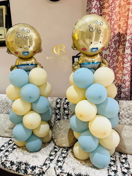 Adorable balloon pillars for a baby boy's welcome home party. These feature columns of pastel blue and yellow balloons topped with large foil balloons shaped like a baby.