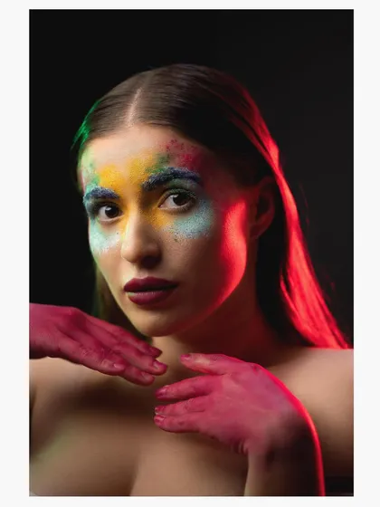 A creative portrait using colored powders on the model's face, lit with contrasting red and green lights for a vibrant, artistic effect.