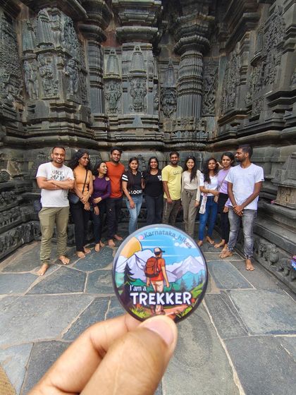Our "I am a Trekker" badge held up in front of the Kalasa temple, a stop on our Kurinjal trek.