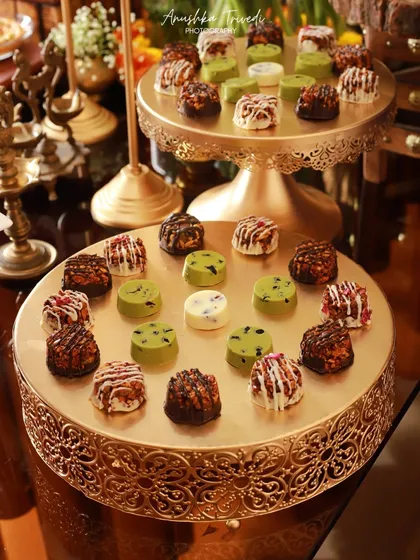 A beautiful display of assorted mini chocolates on tiered golden stands. This shot captures the opulence and variety of a dessert table at a festive event.