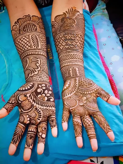 An intricate Indian mehandi design with a mix of paisleys, florals, and leaf motifs, covering the full palm and wrist.