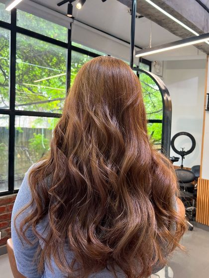 A closer look at the rich brown tones, styled into soft waves that show off the color's dimension and shine.