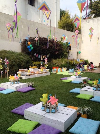 A low-seating picnic arrangement with colorful cushions and hanging kites. This setup is perfect for a casual and fun outdoor gathering.