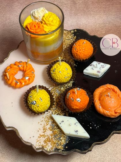 Bringing the taste of festivities to life with our Mithai-shaped candle collection. This platter showcases our handmade candles shaped like laddoos, gujiyas, and barfis, along with a layered glass candle.