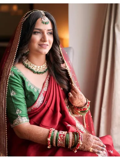 A contemporary bride in a stunning red saree-style lehenga. Samruddhi's look is a beautiful blend of modern styling and traditional colors, with a natural, glowing complexion.